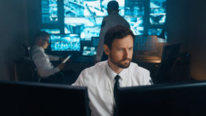An employee of security, security, police, rescue service, FBI, CIA, sits at his workplace behind monitors.