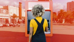 Woman with afro hairstyle using red ATM machine