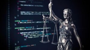 Justice statue with code on monitor device in background