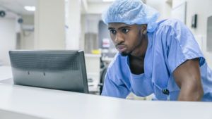 Black doctor using computer in hospital
