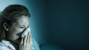 Woman blowing her nose in bed