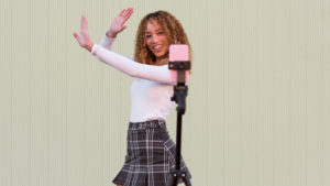 Cheerful Hispanic woman going live on smartphone