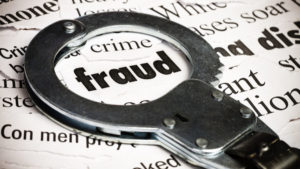 Handcuffs over newspaper with the word fraud
