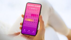 Woman tracking periods by using menstrual calendar app on phone