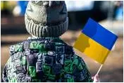 A kid in warm clothes holds a flag of Ukraine