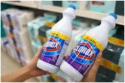 Someone holding up two bottles of Clorox in a store